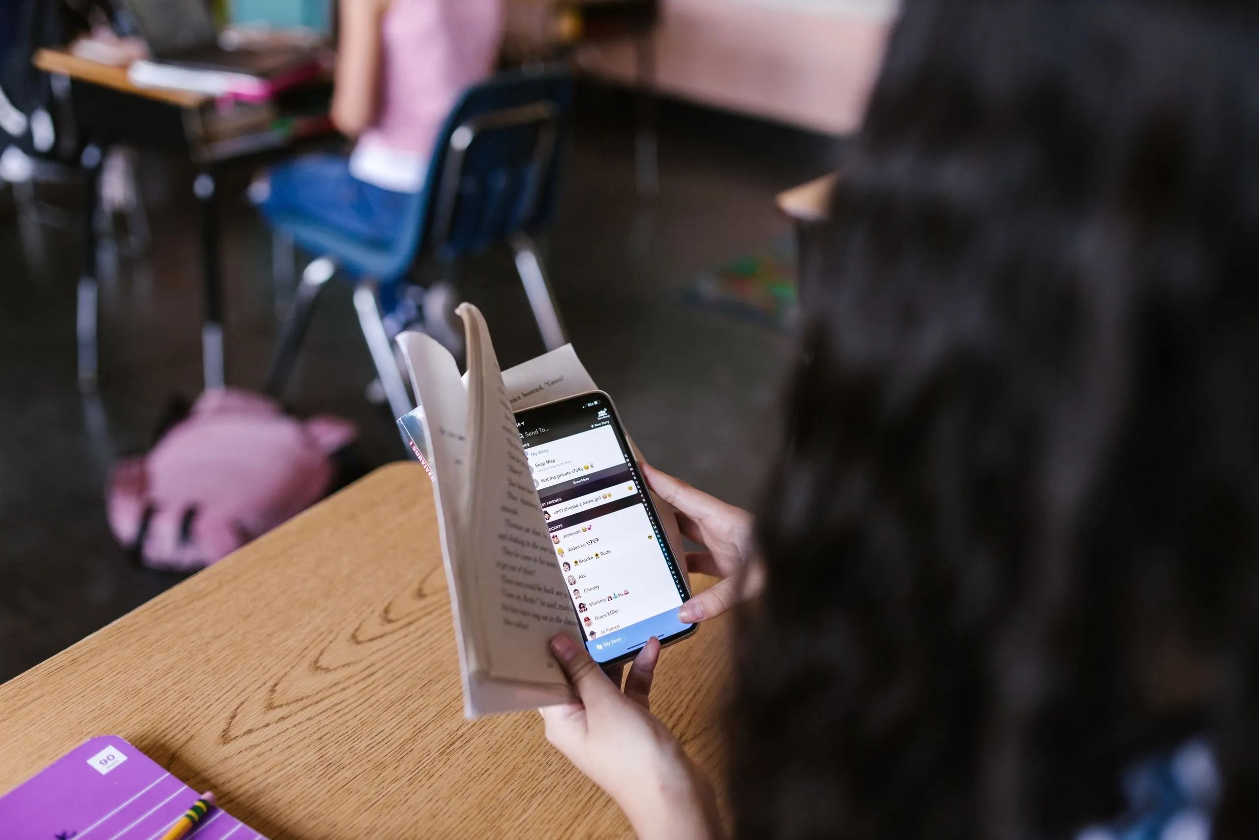 Élève ouvrant l'application Pronote sur son smartphone dans une salle de classe, écran de connexion visible
