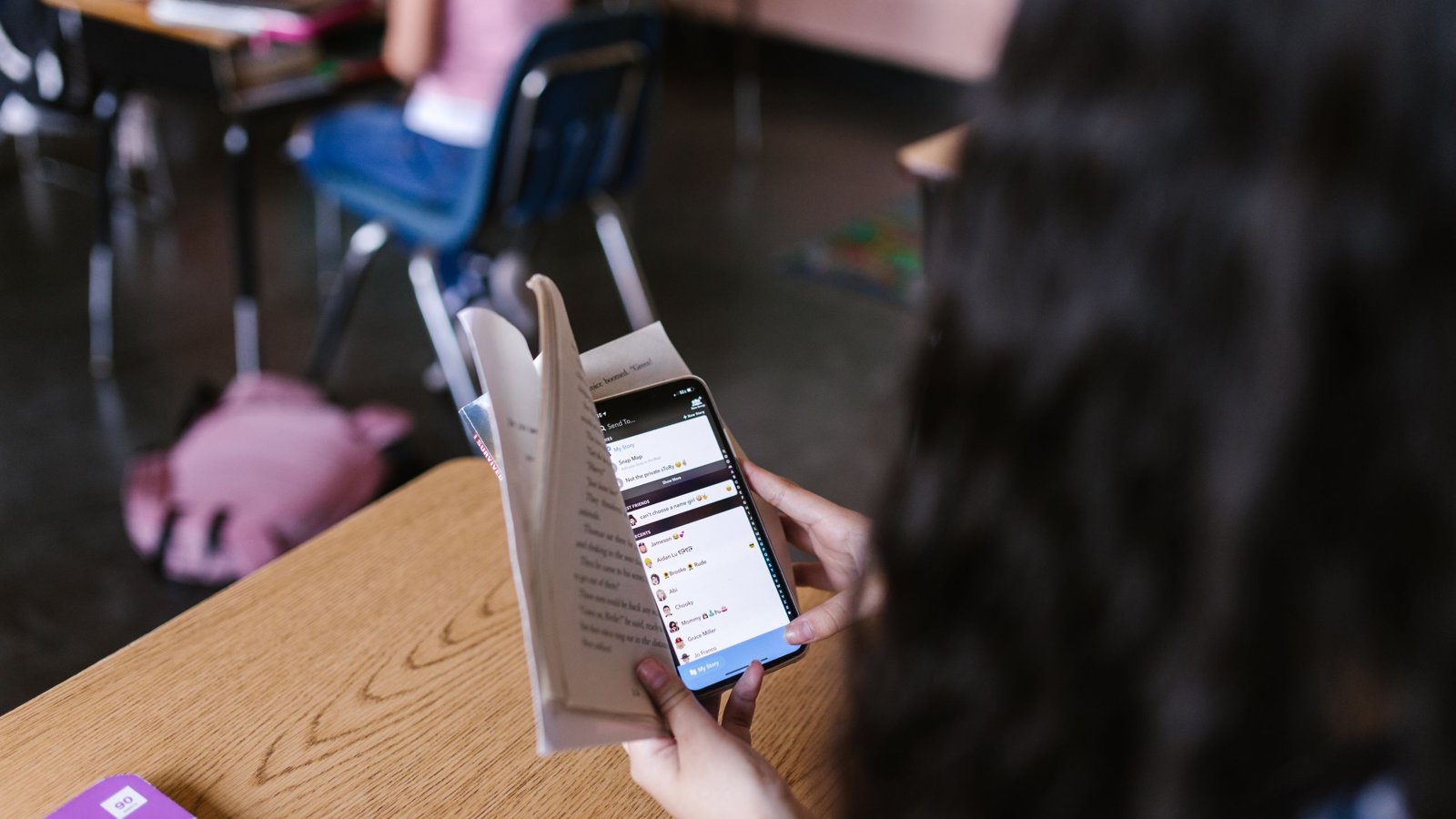 Élève ouvrant l'application Pronote sur son smartphone dans une salle de classe, écran de connexion visible